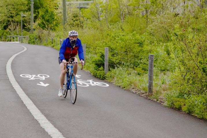 a bicyclist wearing a mask rides in the park