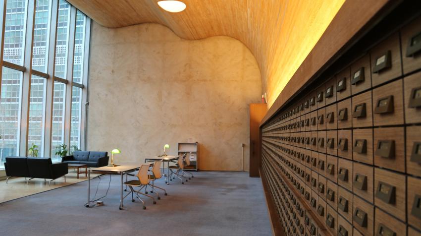 View of the reading room from the other side of the space with cabinets on the left and seating areas in the middle and right. 