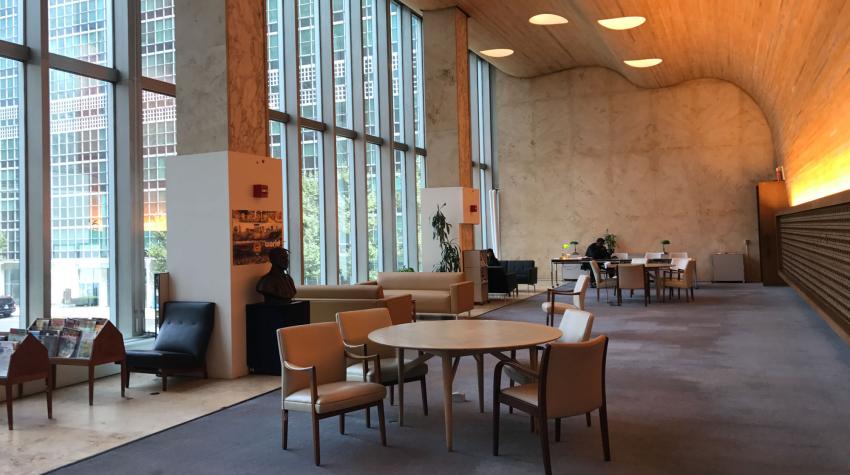 View of the reading room with seating areas near the glass wall and tables in the center of the room. 