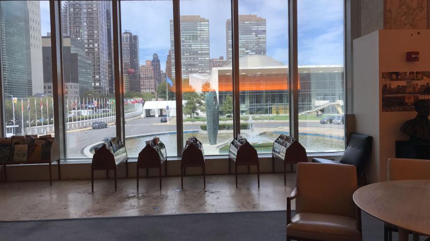 Newstands lined up against a glass wall with seating areas in front. 