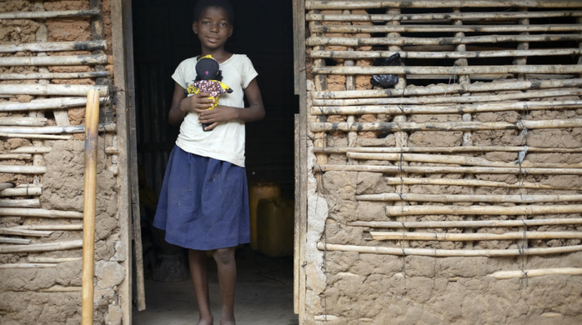 girl in doorway holds doll