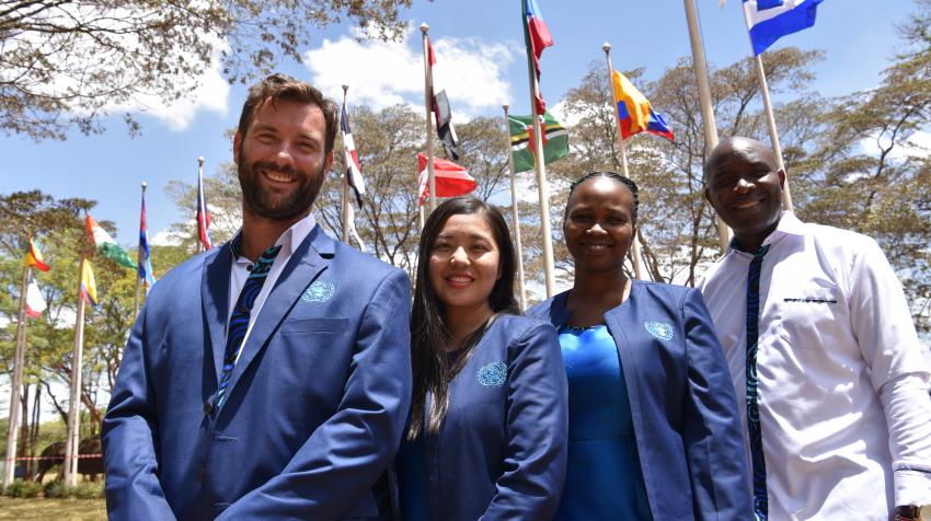 The UN Tour Guides in Nairobi invite visitors to the lush complex to learn more about the UN and its important work. The team is standing in front of the flags. 