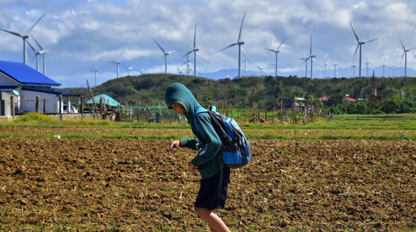 ADB/AlB enavente. Un écolier passe devant un parc éolien aux Philippines.