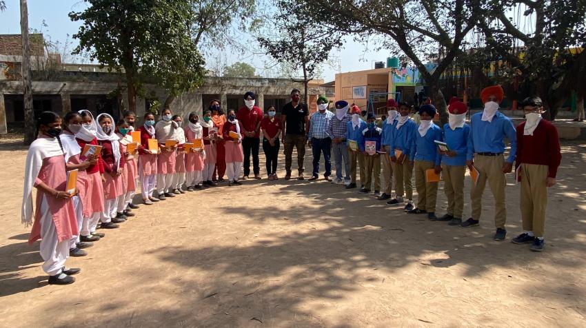 Volunteers from Chitkara University (center) pose with students of the government school in Tahu Village in the State of Punjab, India, during a book distribution event, part of the 3R Campaign 2030, 4 March 2021. Photo courtesy of Chitkara University.