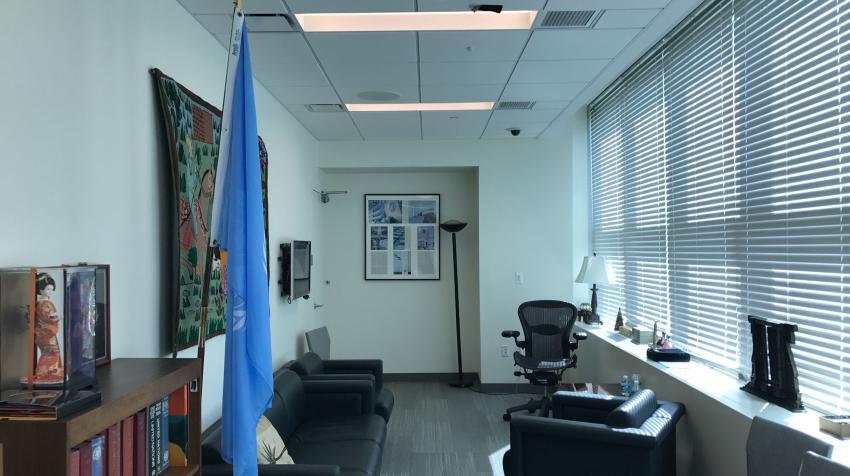 View of Green Room from the entrance with black couches and a UN flag in front.