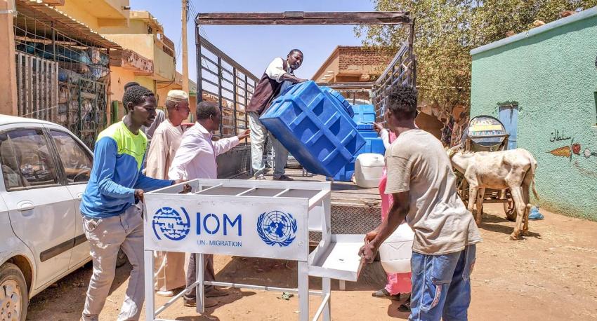 men unload portable handwashing facilities from IOM truck