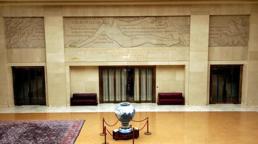 Bird's eye view of the lobby with carved stone artwork on the upper wall and artwork in the center resembling a globe. 