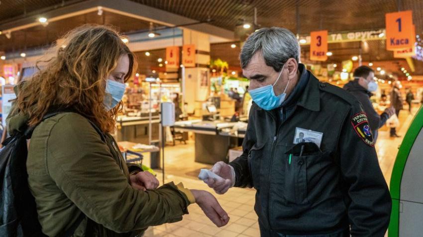 Le vigil d'un grand magasin prend la température d'une cliente à l'entrée.