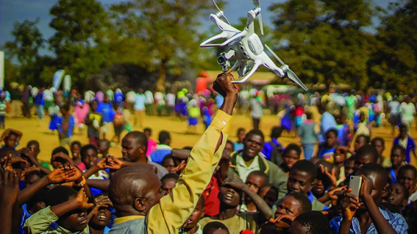 سكان كاسونجو، وسط ملاوي، يتجمعون في مظاهرة لتقنية الطائرات بدون طيار (الطائرات المسيّرة). تقوم حكومة ملاوي واليونيسيف باختبار استخدام الطائرات المسيّرة للأغراض الإنسانية. 28 حزيران/ يونيو، 2017. ©UNICEF/UN070228/CHISIZA