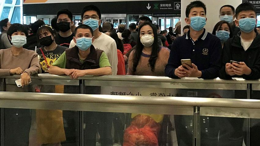 Des personnes portant un masque attendent dans le hall des arrivées dans un aéroport en Chine.