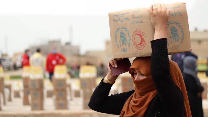 Une femme porte des cartons d'alimentation livres par le PAM en Syrie.