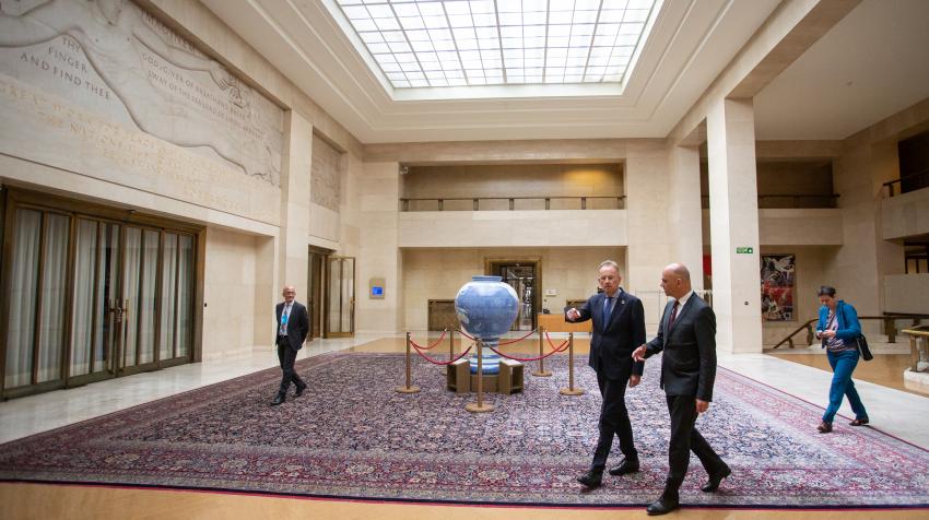 General view of the lobby with a large rug covering the entire floor and an artwork in the center of the council that resembles a globe. 