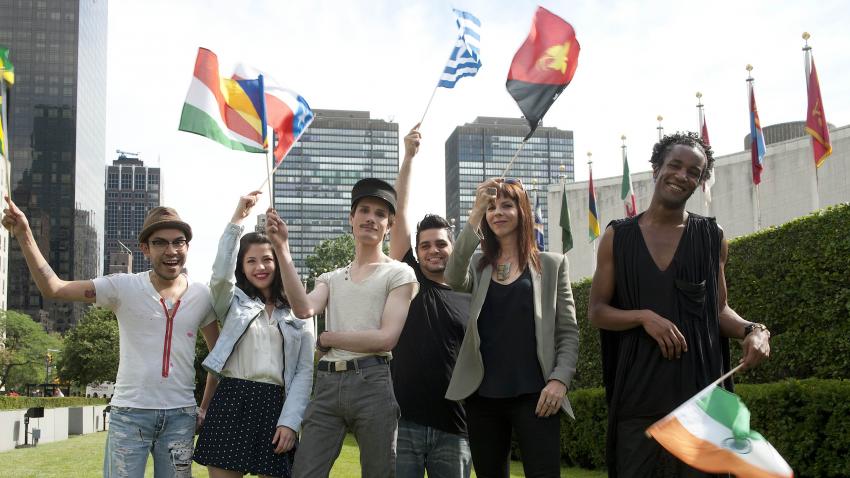 Participants of Project Runway standing at the lawn of the UN Headquarters with the world flags. 