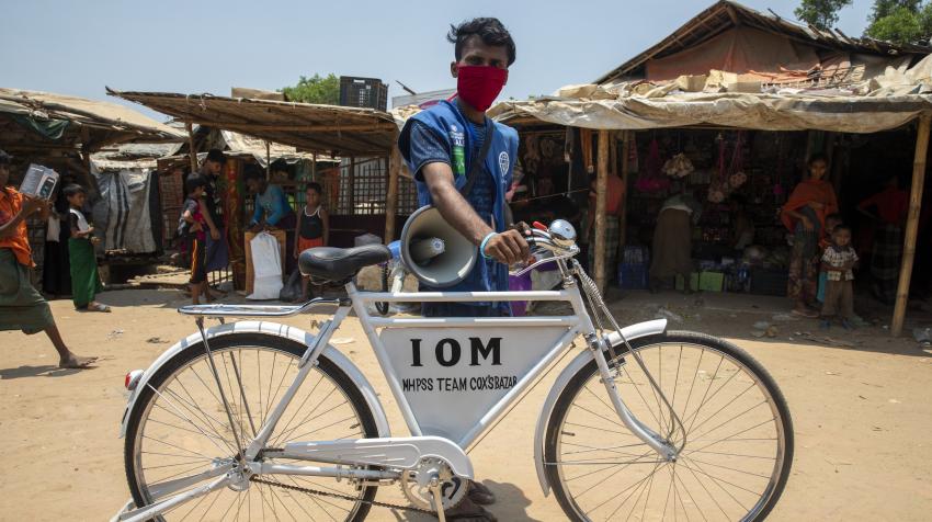 A cyclist with megaphone at a refugee camp
