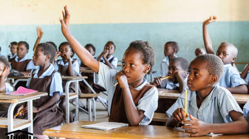 Students in Zambia raise their hands to answer questions posed by their teacher.
