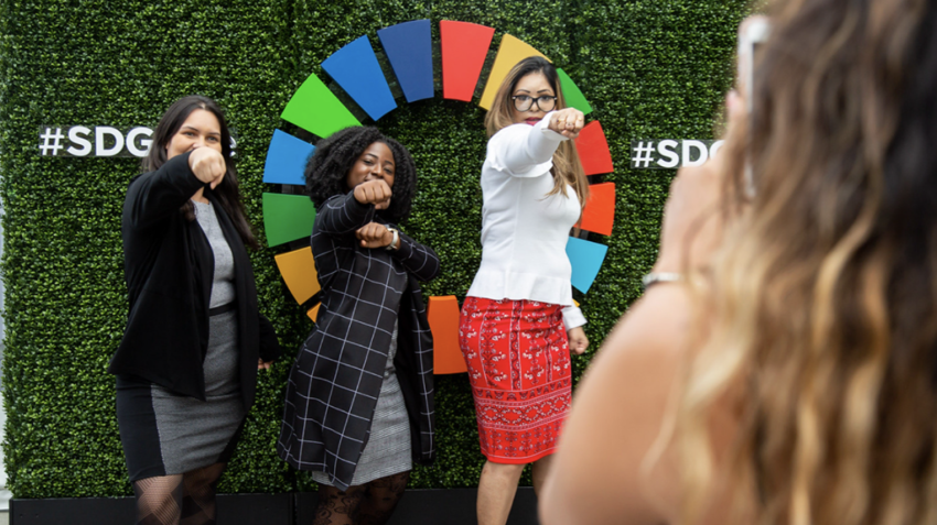 Youth pose in front of SDG banner