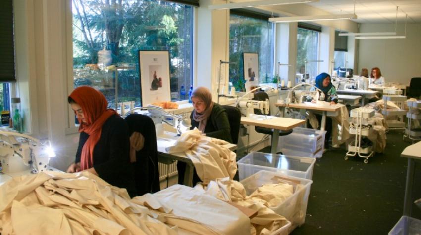 Mujeres trabajando en un taller de costura frente a máquinas de coser