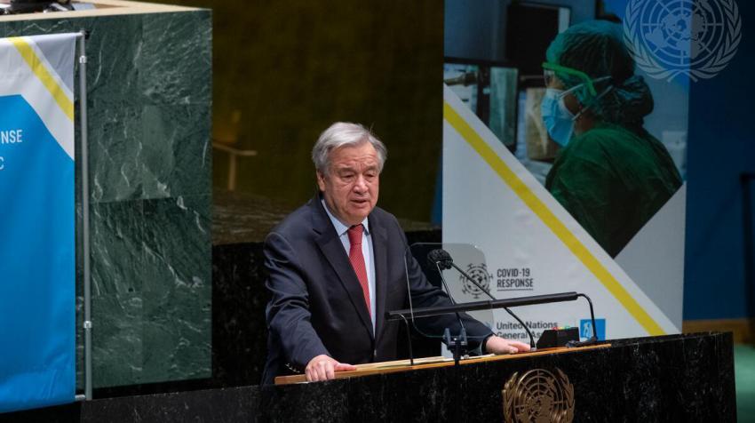 Secretary-General António Guterres at a podium with COVID-19 poster