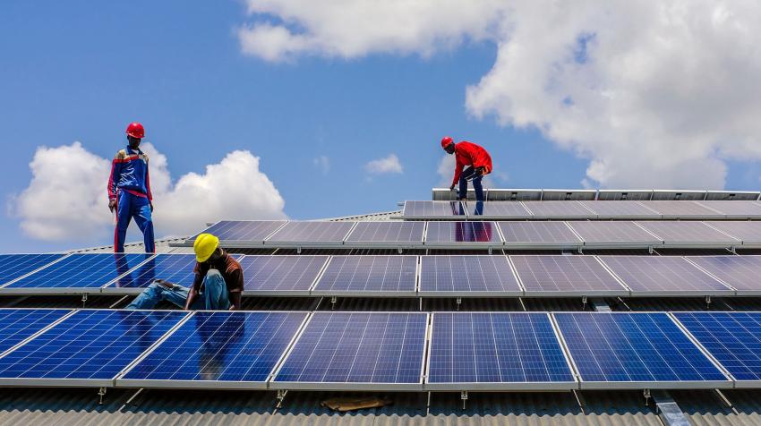 Des techniciens installent des panneaux solaires sur le toit d'un bâtiment.