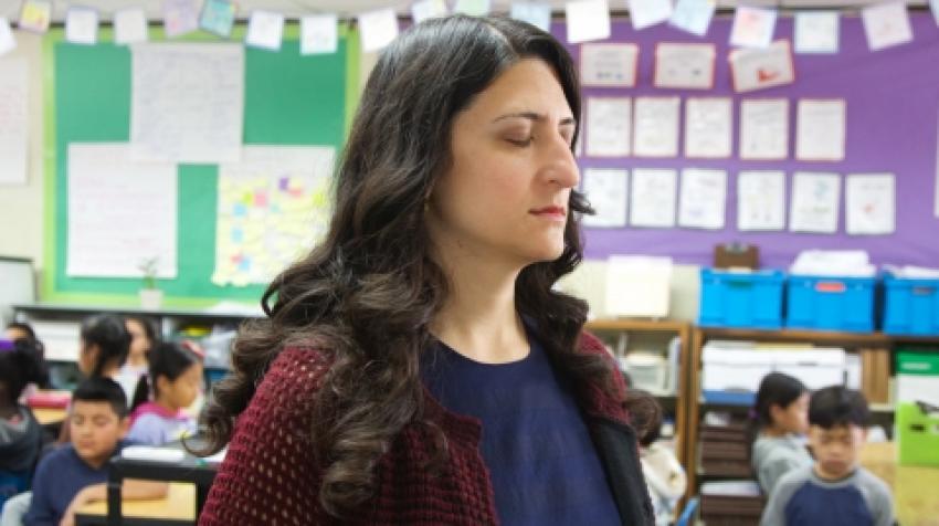 Teacher meditating in a classroom.