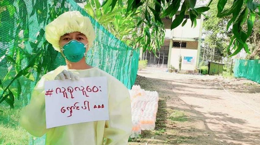 Min Min holds a sign saying "avoid crowds" at the quarantine center in Pyay where he worked as a volunteer. Photo courtesy Min Min.