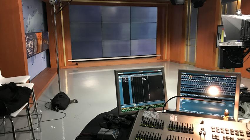 View of the TV studio with a mixing console in front of a news set.  