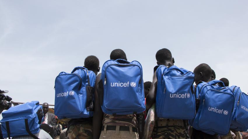 Children released from armed groups are in a circle, with blue UNICEF backpacks. 