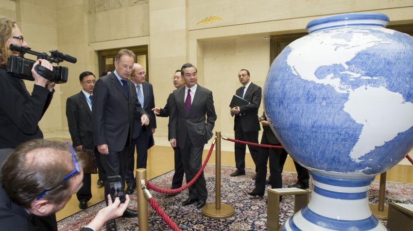 People are surrounding the globe artwork in the middle of the lobby. 