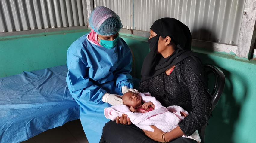 Midwife Rotna speaks with Minara about her newborn baby. Maternal health services are continuing despite the pandemic.