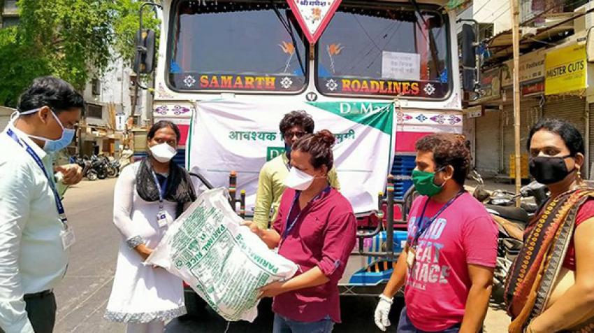 People wearing facemasks receive a bag in front of a bus.