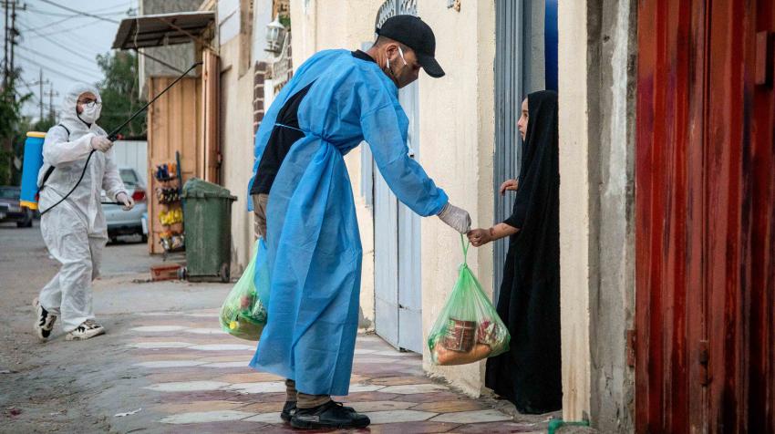 Un voluntario proporciona comida a una niña en un barrio residencial.