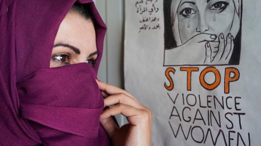 Woman wearing a hijab looks at a poster.