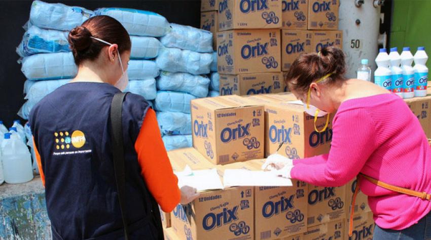 Deux femmes en train de comptabiliser la livraison de cartons de fournitures de kits d'hygiène destinés aux femmes vivant dans les prisons et les centres de quarantaine.