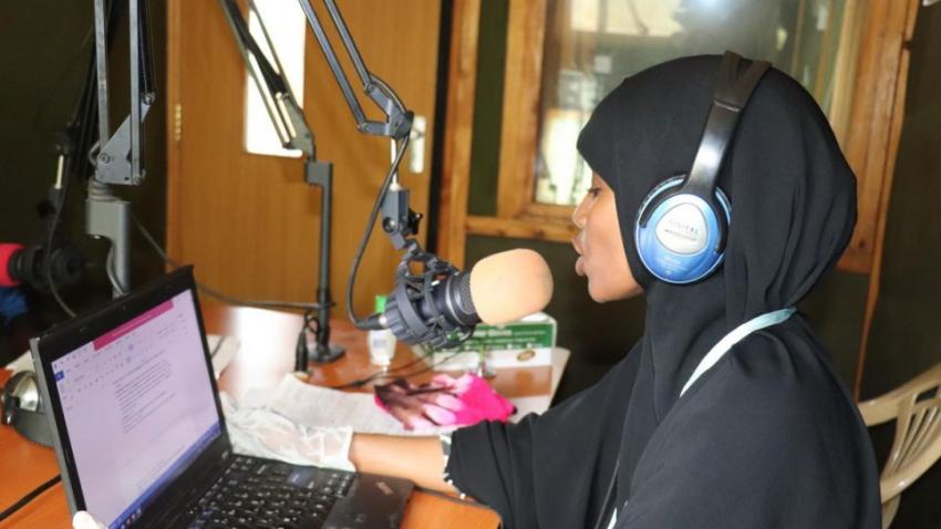Mujer hablando frente a un micrófono en un estudio de radio
