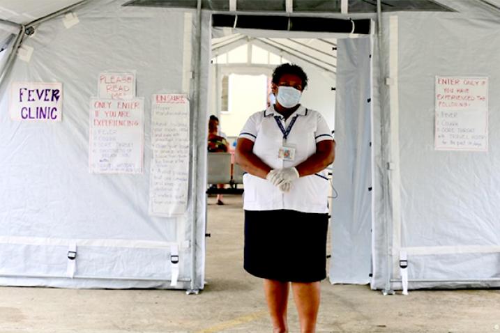 Woman with a face mask stands in front of a tent.