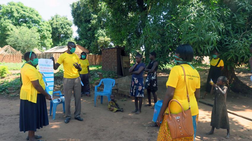 Des femmes dans un quartier à Yambio utilisent des documents d'information produits par la Mission des Nations Unies au Soudan du Sud pour sensibiliser la population à la COVID-19.