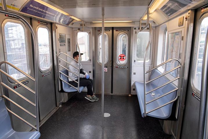 Man with face mask in empty subway car.