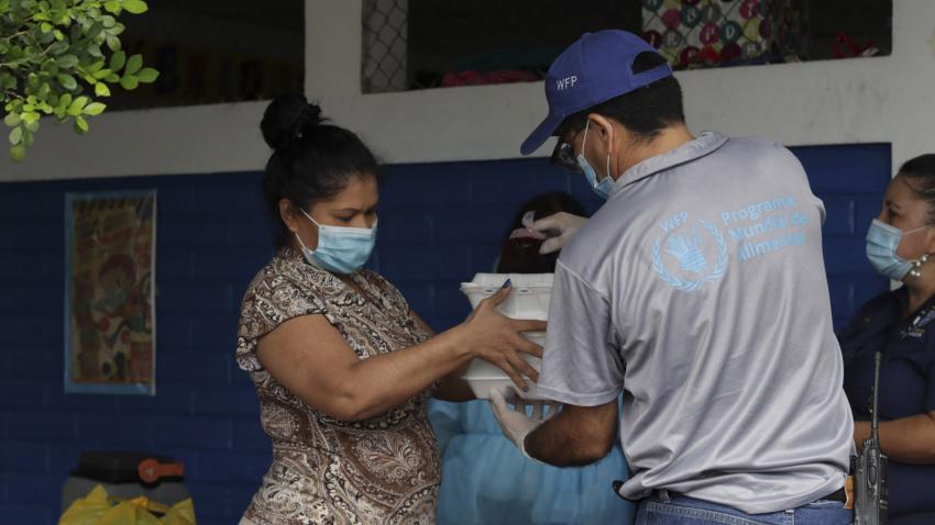 Un employé du Programme alimentaire mondial distribue de la nourriture à une femme au Salvador