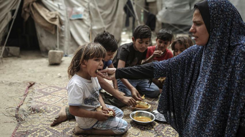 Une femme dans une camp de refugies nourrit son fils.