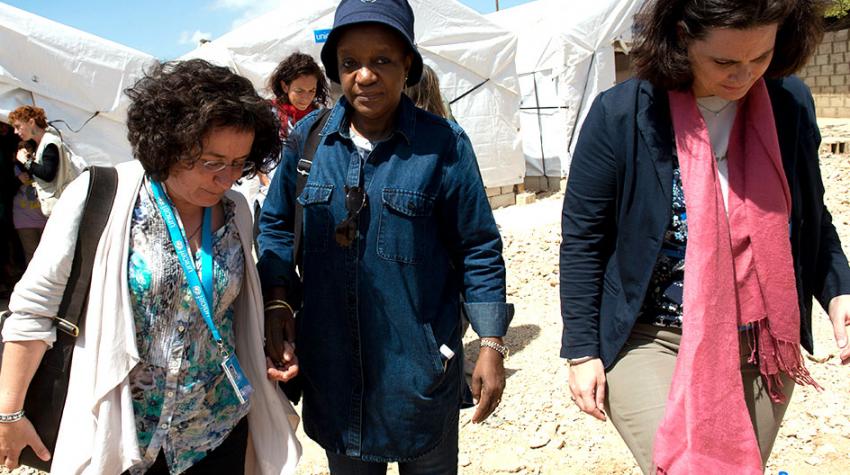 Ms. Bangura walks with two women and looks at the camera with sad eyes.