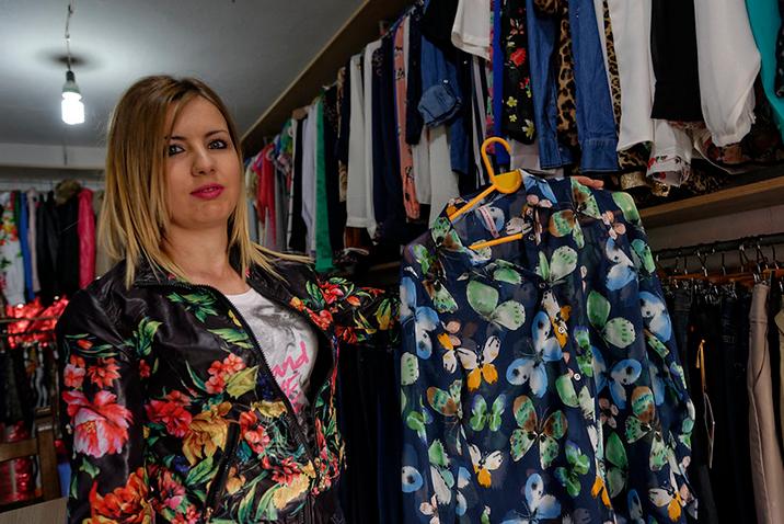 A woman holds up a blouse