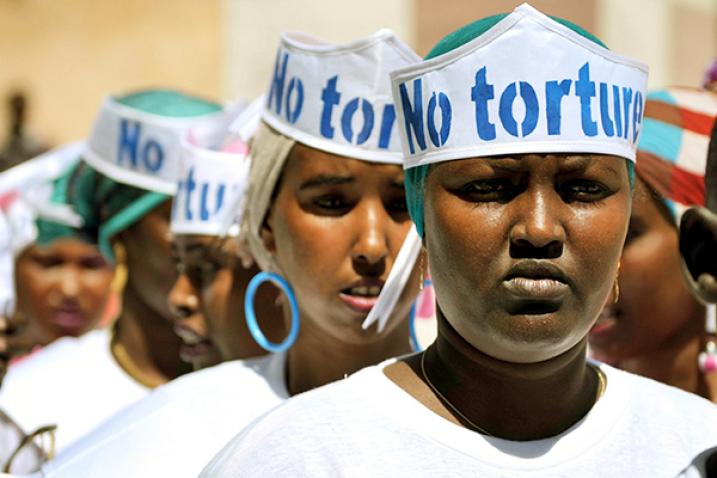 People wearing hats that read “No Torture” form a line. 