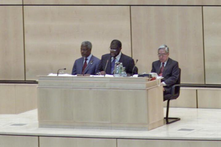 General Assembly President Theo Ben Gurirab sits at the podium, with two men sitting behind him on either side.