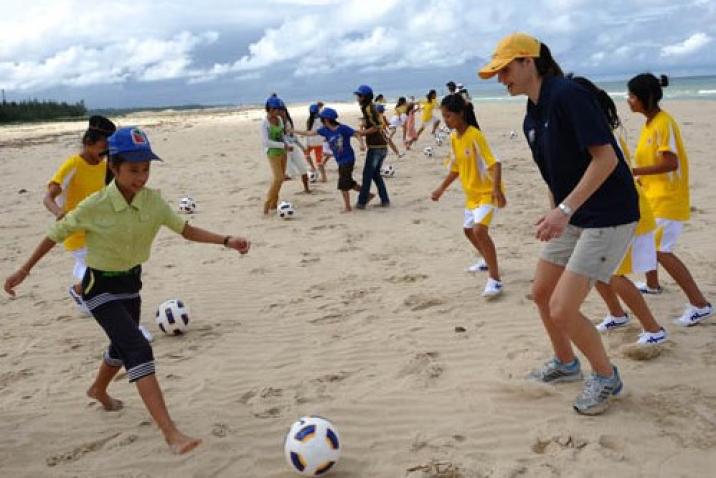 Children play soccer on a beach.
