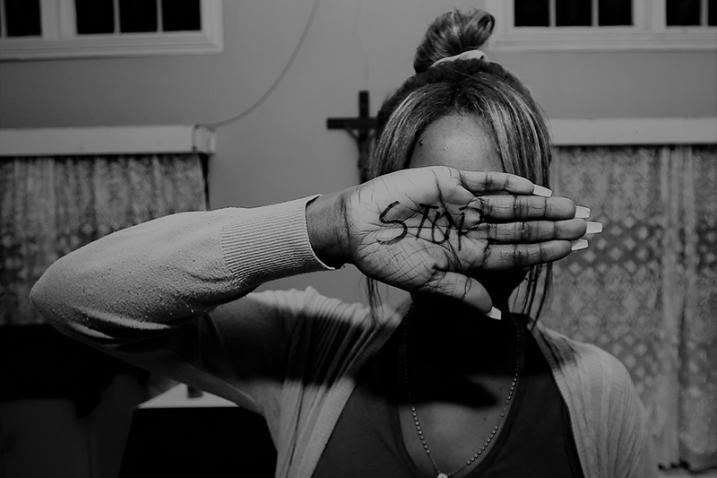 woman hiding behind her hand with Stop written on it