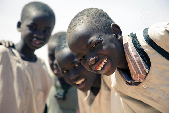 Four children in the Sudan facing camera and smiling.