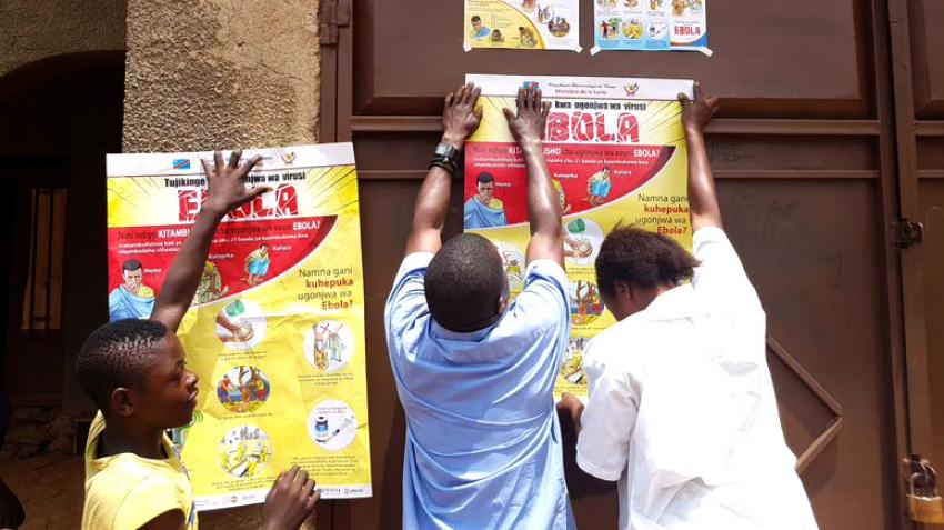 Three people hanging posters.