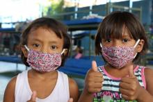 children with masks showing thumbs up