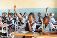 Students in Zambia raise their hands to answer questions posed by their teacher.