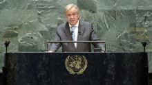 The Secretary-General speaking at a black marble podium with a golden UN emblem. 